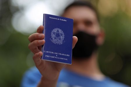 Trabalhador mostra carteira de trabalho ao procurar por oportunidades de emprego no centro de São Paulo
