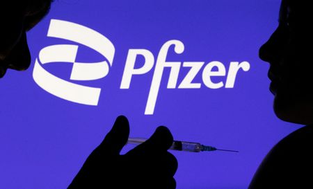 Silhueta de pessoa sendo vacinada em frente a logo da Pfizer em foto de ilustração