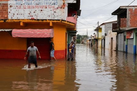 Pessoas caminham por ruas alagadas em Itajuipe, na Bahia