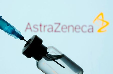 Frasco e seringa em frente ao logo da AstraZeneca em foto de ilustração