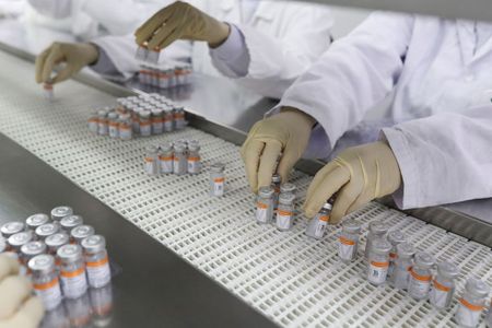 Funcionários manuseiam frascos com doses da vacina contra Covid-19 CoronaVac no Instituto Butantan, em São Paulo
