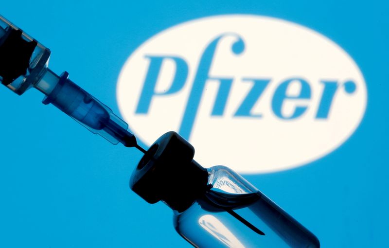 Frasco e seringa à frente de logo da Pfizer em foto de ilustração