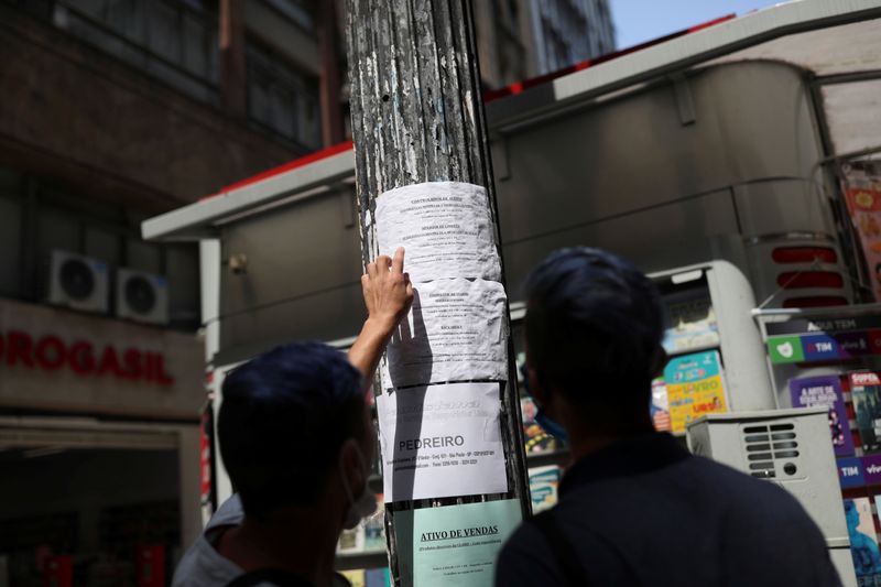 Pessoas avaliam oportunidades de emprego em cartaz no centro de São Paulo