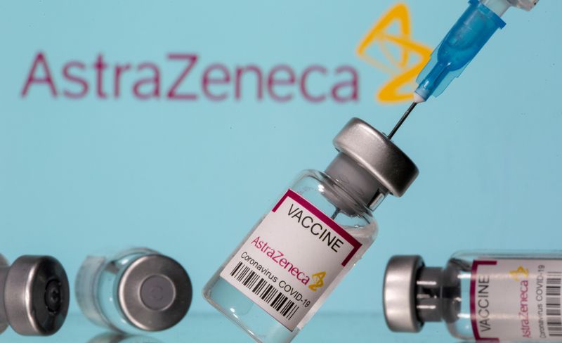Frascos rotulados como de vacina da AstraZeneca contra Covid-19 em frente ao logo da empresa em foto de ilustração