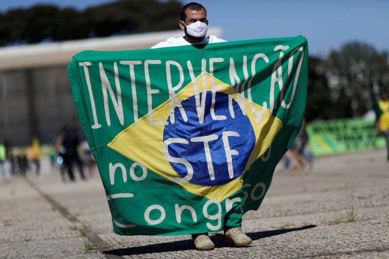 Manifestante com bandeira que defende intervenção no STF e no Congresso durante ato em Brasília