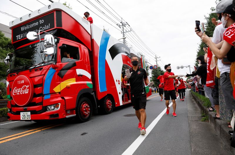 Caminhão de patrocinador e equipe de organização no primeiro dia do revezamento da tocha olímpica em Tóquio