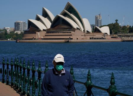 Homem com máscara caminha em frente à Casa da Ópera de Sydney