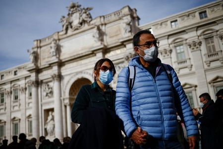 Pessoas usando máscara de proteção passam em frente à Fontana de Trevi em Roma