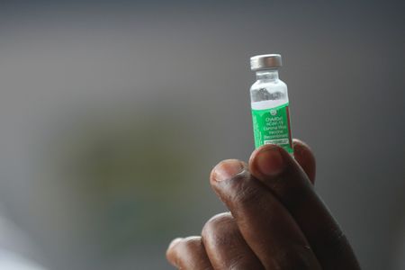 Profissional da Fiocruz segura dose da vacina Oxord/AstraZeneca envasada na fundação