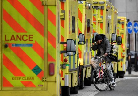 Homem em bicicleta passa ao lado de ambulâncias estacionadas em hospital de Londres em meio à pandemia de Covid-19
