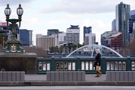 Mulher usando máscara de proteção caminha sozinha em Melbourne em meio à pandemia de Covid-19