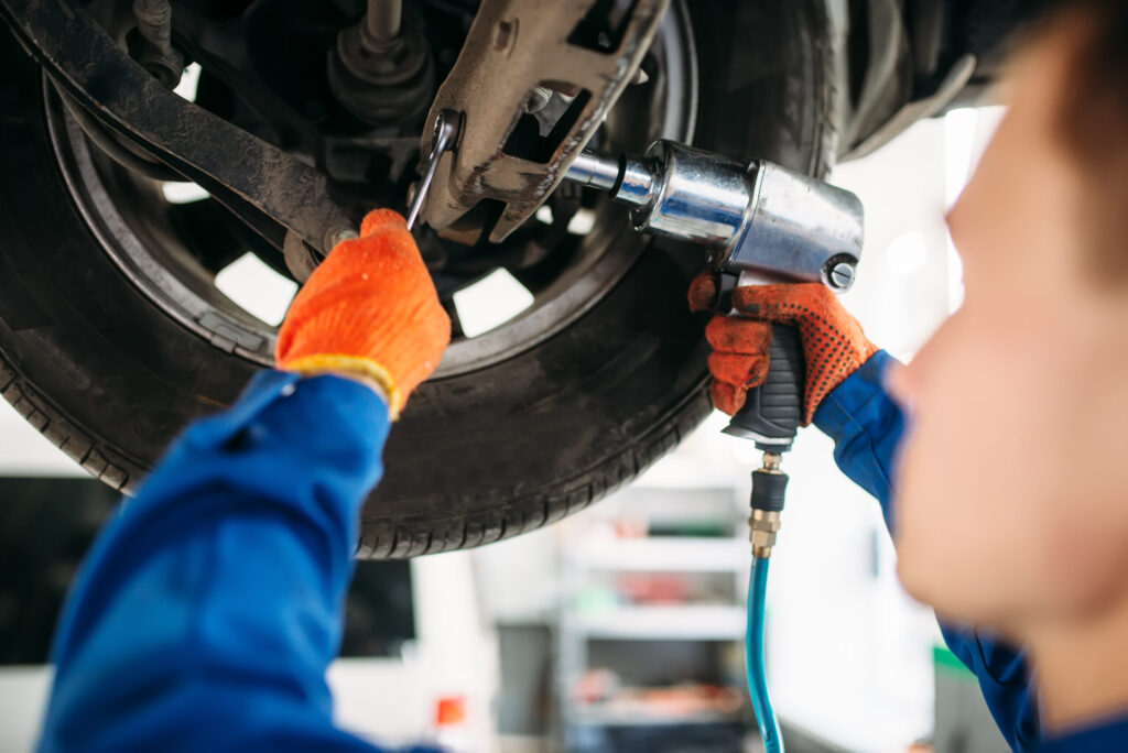 Technician with a wrench repair car suspension Technician with a wrench repair car suspension
