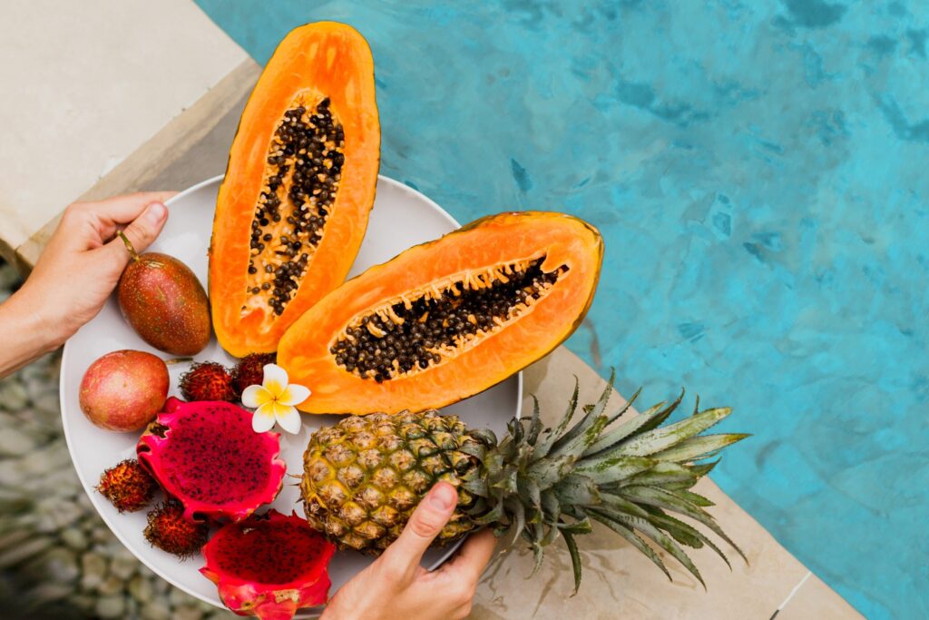 Woman holding plate of tasty tropical exotic fruits on the edge of pool Woman holding plate of tasty tropical exotic fruits on the edge of pool