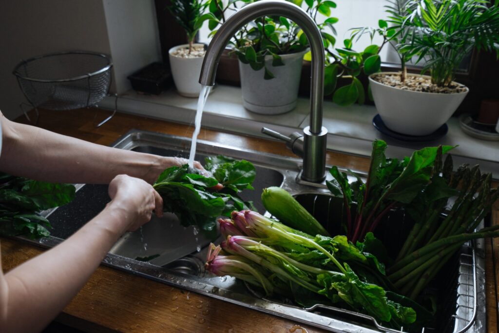 Woman washing fresh vegetables in kitchen Woman washing fresh vegetables in kitchen