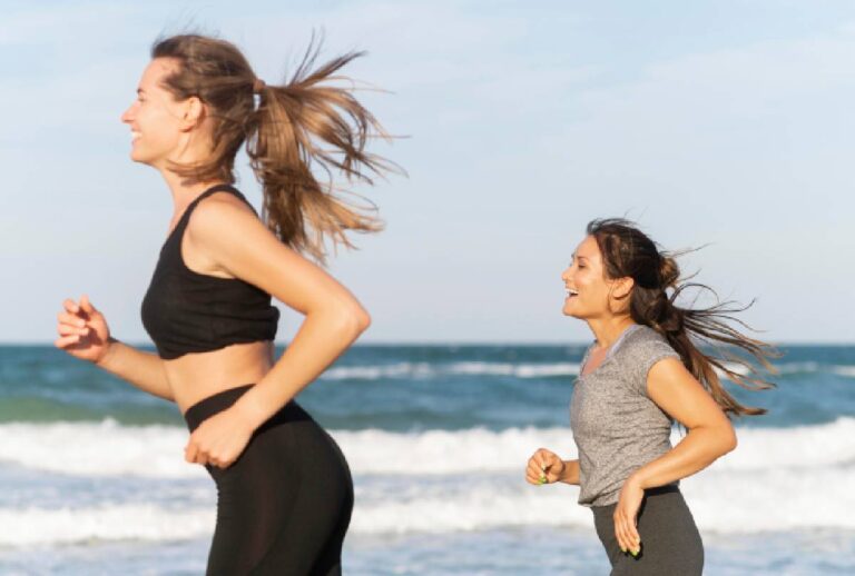 Mulheres correndo e fazendo exercícios na praia à beira-mar.