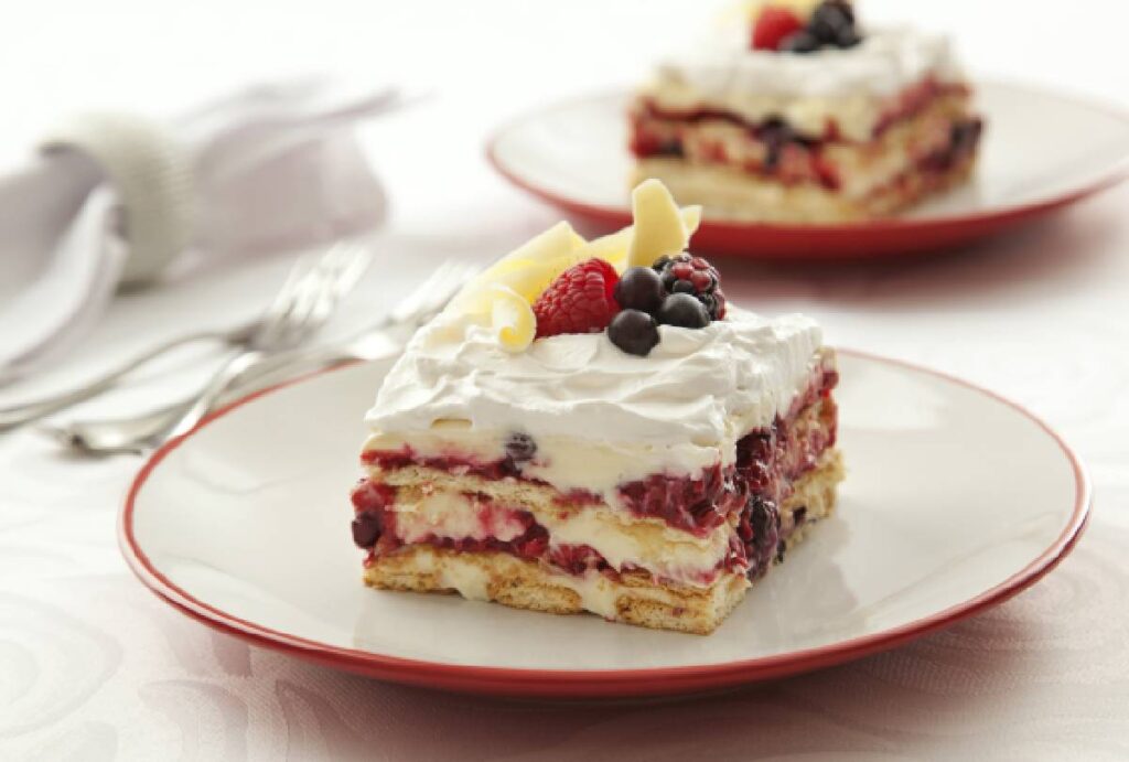 Fatia de pavê de chocolate branco com calda de frutas vermelhas
