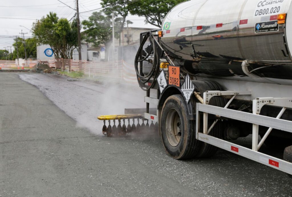 Caminhão passa asfaltando rua.