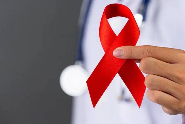 Profissional de saúde segurando fita vermelha simbolizando a prevenção do HIV