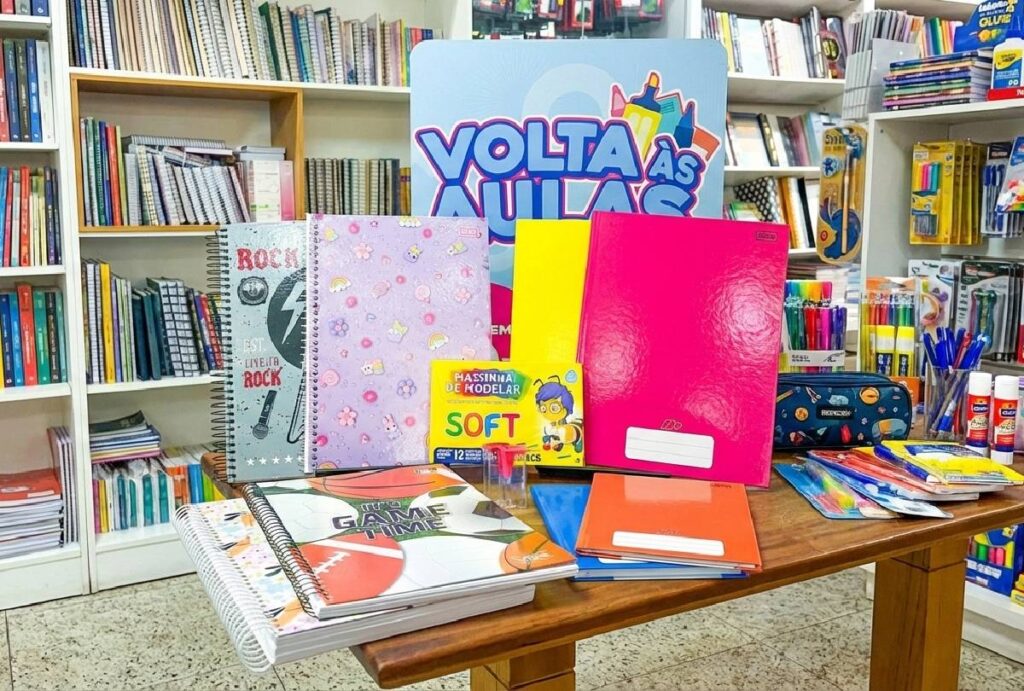 Kit de material escolar com desconto sobre mesa com prateleiras de livraria ao fundo