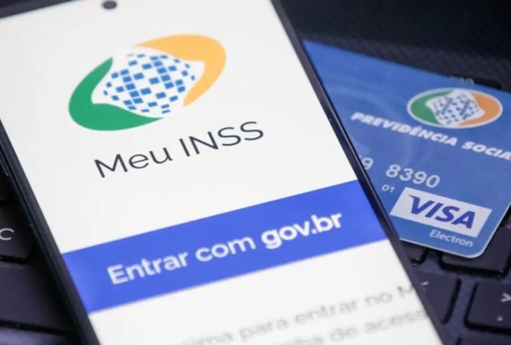 Celular com aplicativo no Meu INSS aberto e cartão da previsdência social no fundo.