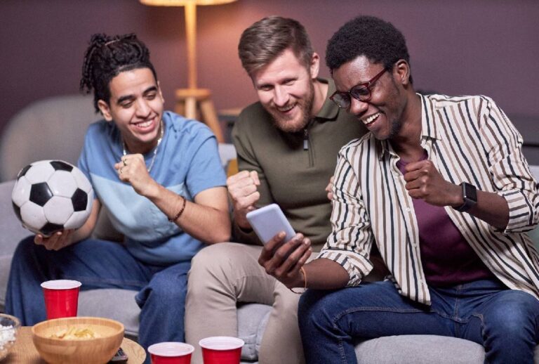 Homens comemorando enquanto veem resultado de jogo no celular