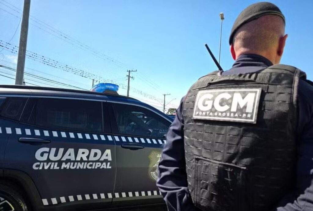 guarda municipal de costas em frente a uma viatura.