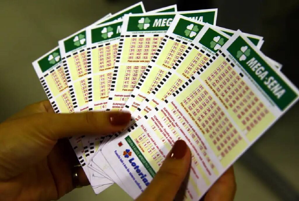 Homem segurando vários bilhetes de aposta da Mega-Sena