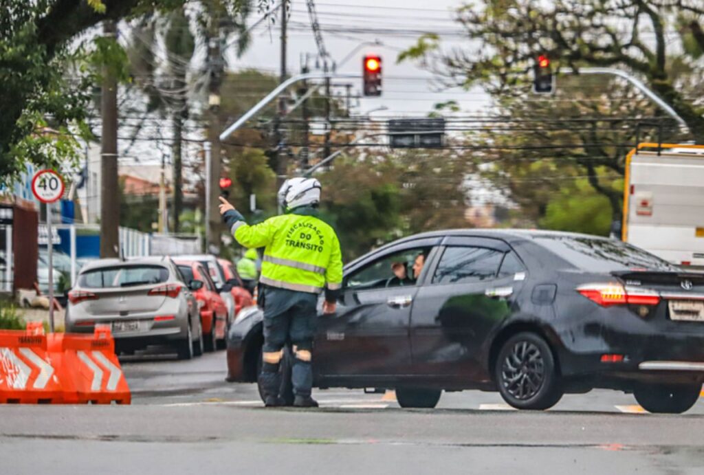 Guardad de trânsito orientando motorista em carro preto.
