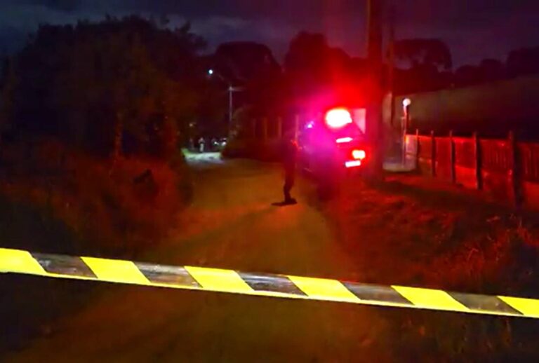 Fita zebrada com viatura do IML ao fundo com as sirenes acesas