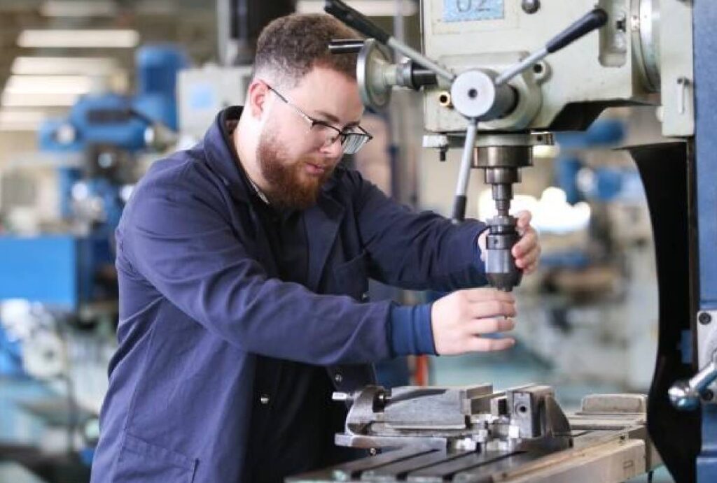 Técnico em eletromecânica fazendo manutenção de equipamento industrial