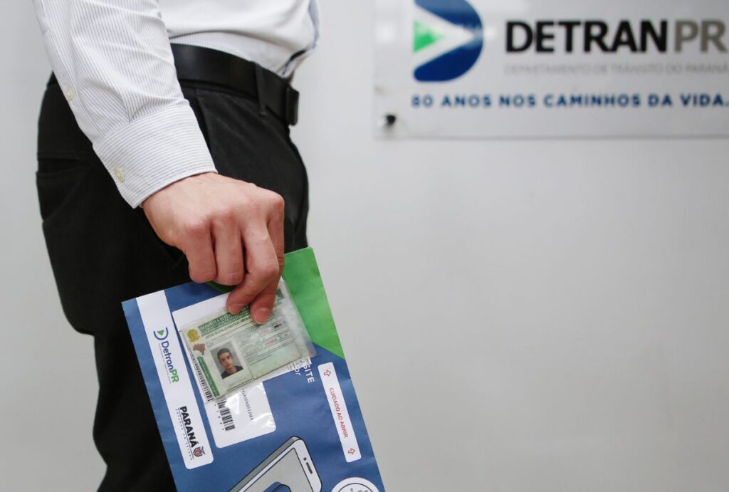 Homem segurando uma CNH no Detran