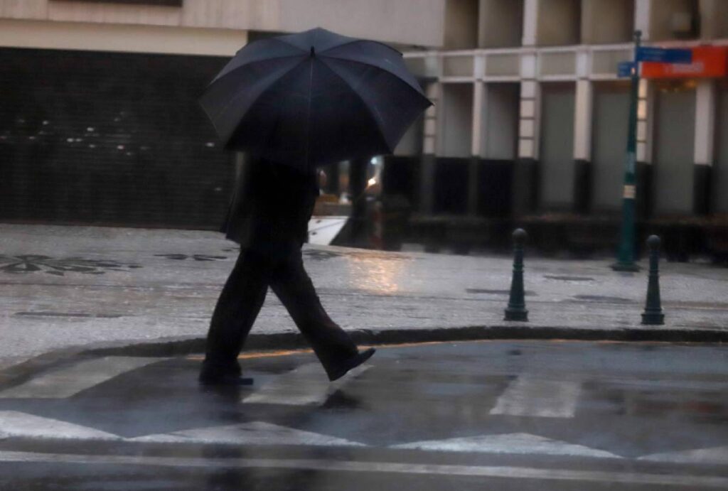 Pessoa atravessando a rua segurando um guarda-chuva