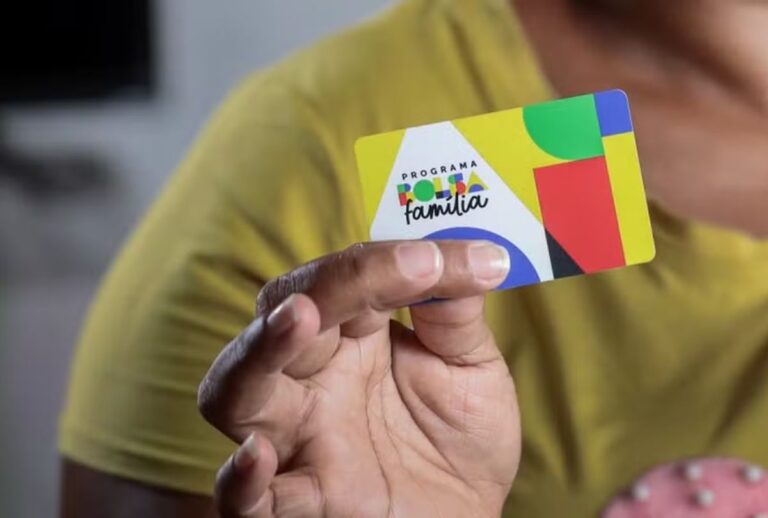 Mulher segurando cartão do bolsa família.