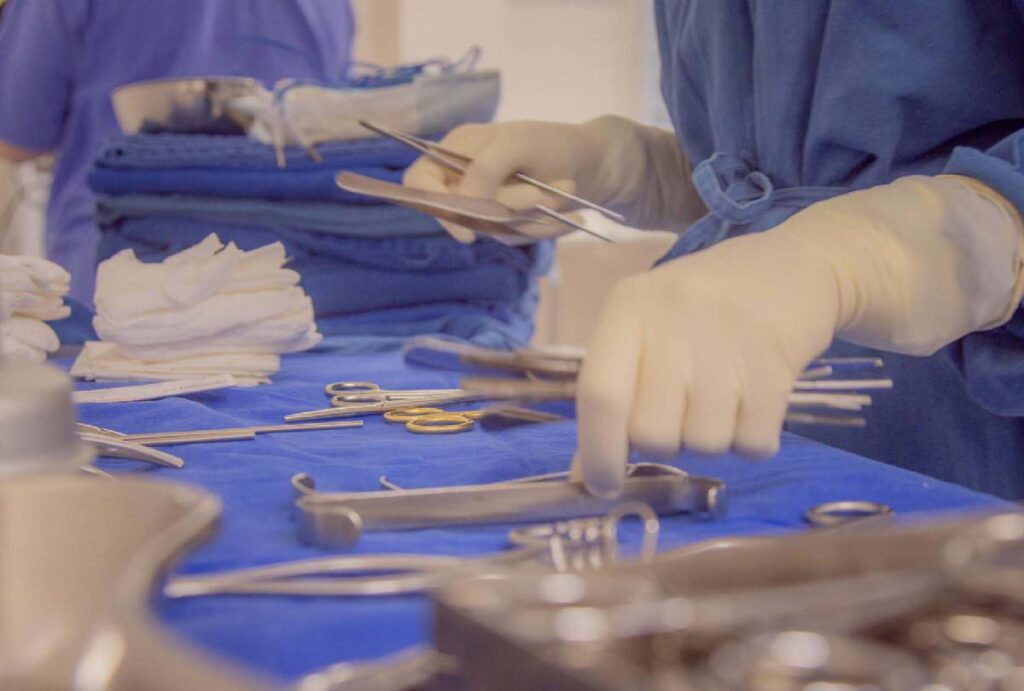 Médicos com luvas cirúrgicas se preparando para iniciar cirurgia com instrumentos