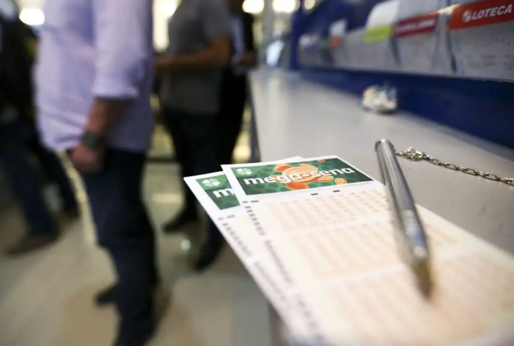 Dois bilhetes da Mega-Sena e uma caneta em cima de um balcão