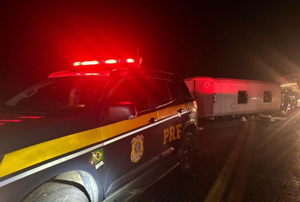 Viatura da PRF ao lado do ônibus tombado