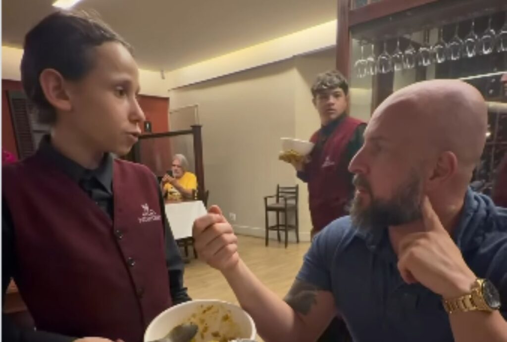 Menino sendo entrevistado em restaurante.