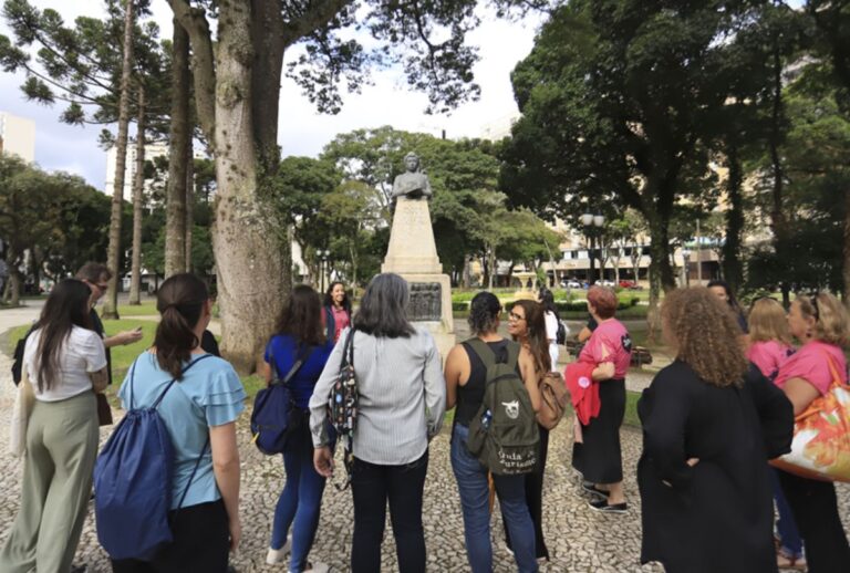 Grupo de pessoas em frente a estátua no centro de Curitiba