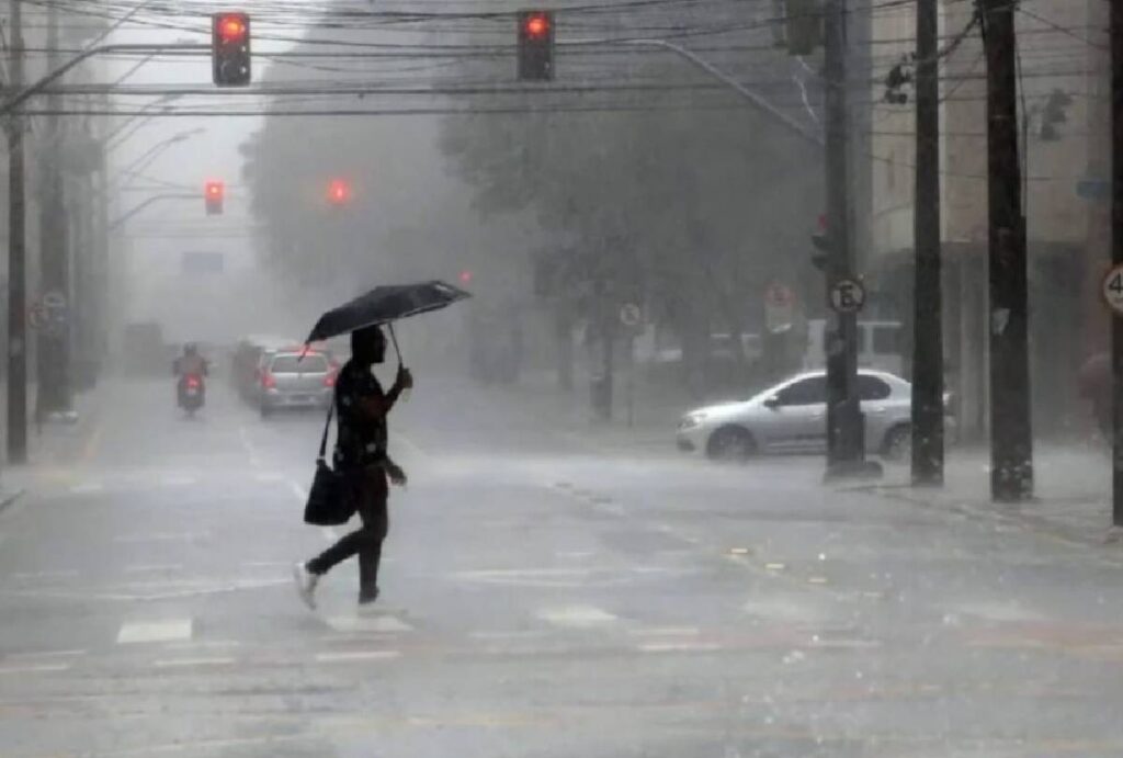 Homem atravessando a rua na chuva