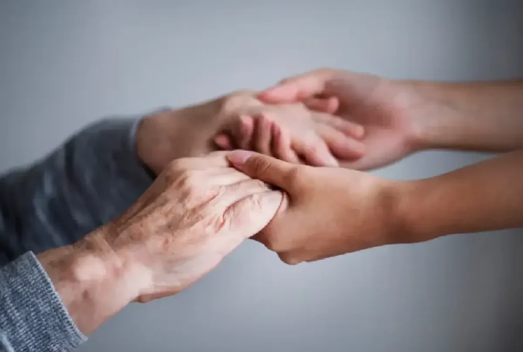 Idosa e jovem de mãos dadas