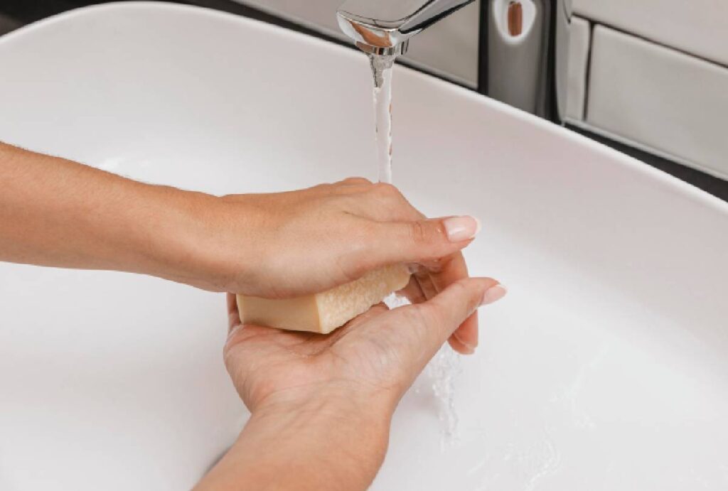 Pessoa lavando a mão na pia