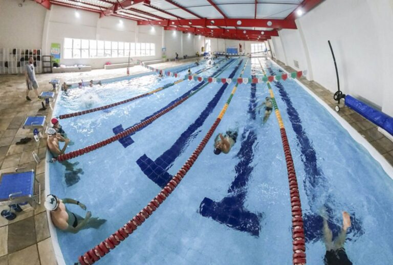 Grupo de pessoas nadando em piscina coberta.