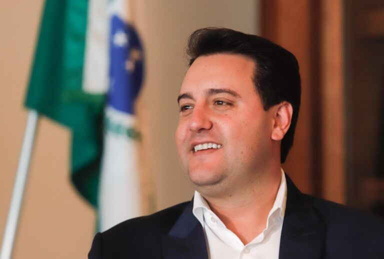 Ratinho Jr com bandeira do Paraná no fundo