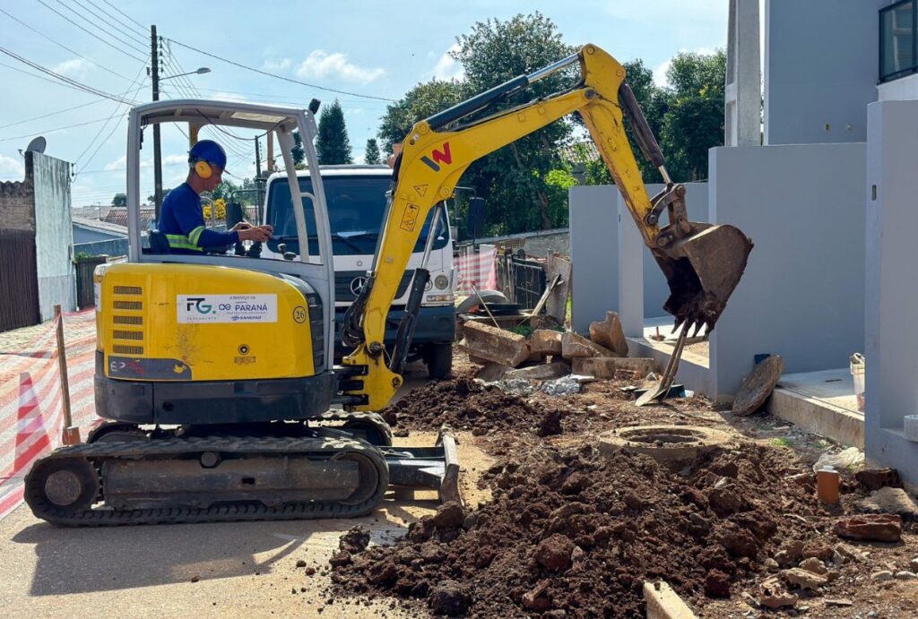 Rua em obras com escavadeira.