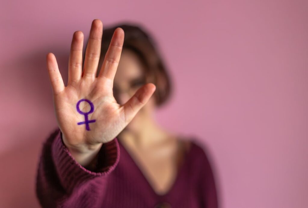 Mulher mostra mão com símbolo do sexo feminino.