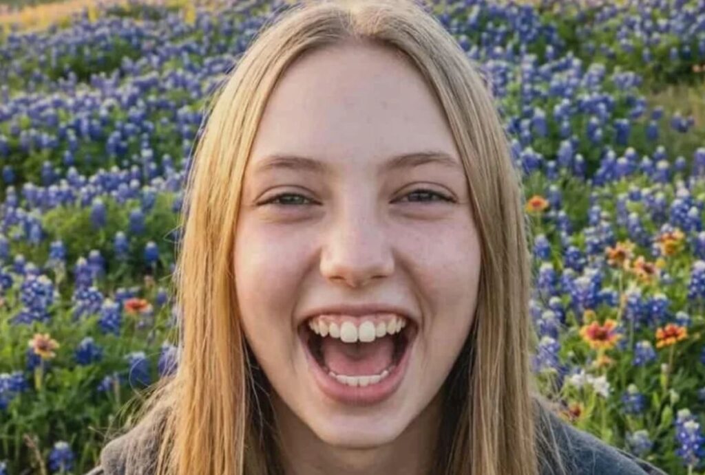 Garota loira sorrindo em um campo florido