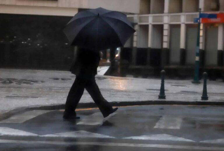 Pessoa atravessando a rua segurando um guarda-chuva