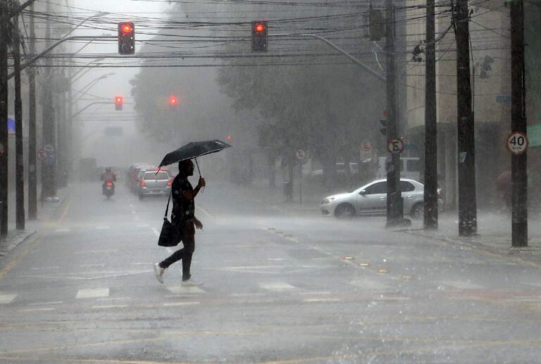Homem atravessando a rua durante uma chuva, com um guarda-chuva