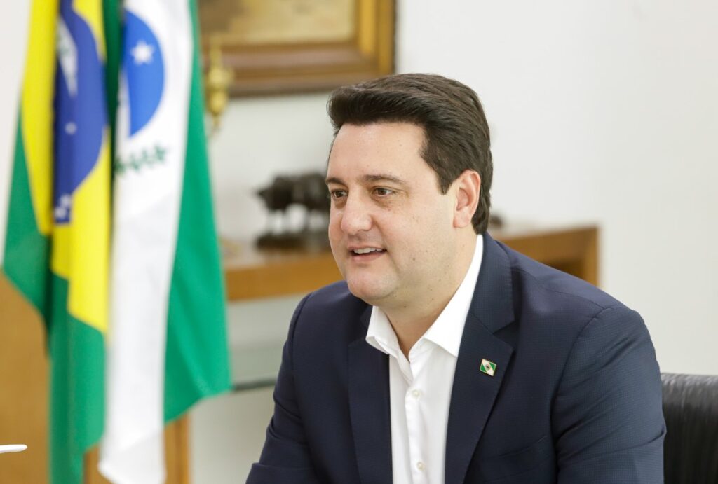 Ratinho Jr com as bandeiras do Paraná e do Brasil no fundo