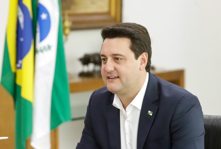 Ratinho Jr com as bandeiras do Paraná e do Brasil no fundo